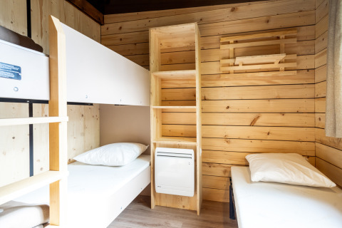 Habitación en Chalet Evasion glamping con literas, estantería de madera y paredes de madera clara.