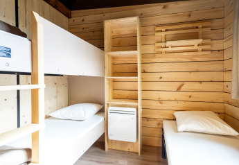 Zimmer im Chalet Evasion Glamping mit Etagenbetten, Holzregal und hellem, natürlichem Licht.