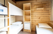 Camera Chalet Evasion glamping con letti a castello, mensole in legno e pareti in legno naturale.