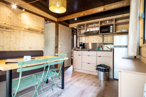 Vista interior del alojamiento glamping Chalet Evasion con paredes de madera, cocina y comedor.