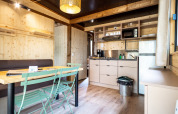 Indvendig udsigt over Chalet Evasion glampingindkvartering med træpaneler, køkken og spiseplads.