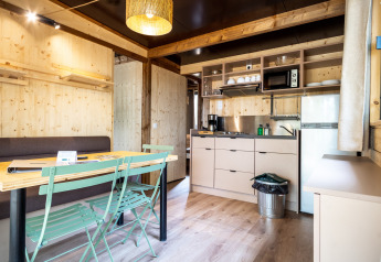 Interieur van Chalet Evasion glamping accommodatie met houten panelen, keuken en eethoek.