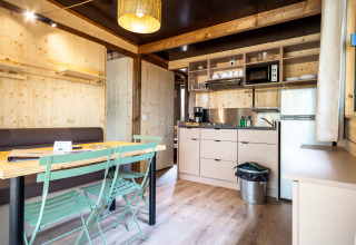 Innenansicht der Chalet Evasion Glamping-Unterkunft mit Holzwänden, Küche und Essbereich.