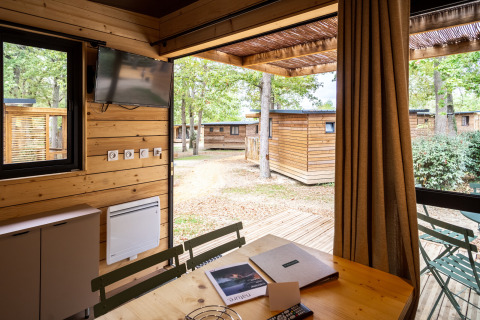 Zicht vanuit het Chalet Evasion glampingverblijf met houten terras en uitzicht op andere hutten buiten.