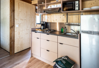 Moderne tekøkken i Chalet Evasion glamping med komfur, vask, kaffe, mikrobølgeovn og køleskab.