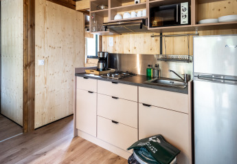 Moderne tekøkken i Chalet Evasion glamping med komfur, vask, kaffe, mikrobølgeovn og køleskab.
