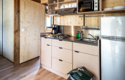 Coin cuisine moderne au Chalet Evasion glamping avec plaques, évier, cafetière, micro-ondes et frigo.