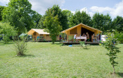 Tienda safari Bungalow Classic en Huttopia La Plage Blanche, Francia, rodeada de naturaleza verde.