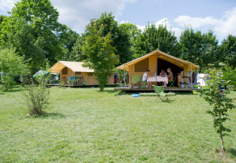 Tienda safari Bungalow Classic en Huttopia La Plage Blanche, Francia, rodeada de naturaleza verde.
