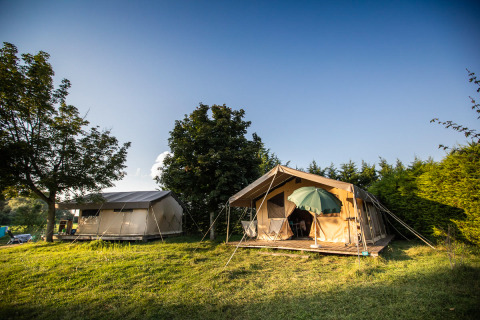 Toile&Bois Safari-Zelt Sweet auf einer Wiese mit Bäumen, aufgenommen an einem sonnigen Tag.