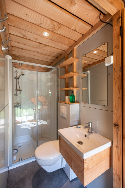 Baño moderno en la tienda Toile&Bois Sweet de Huttopia La Plage Blanche, Francia, con detalles de madera.