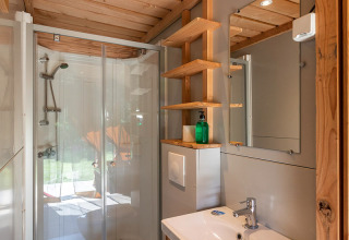 Bagno moderno nella tenda Toile&Bois Sweet di Huttopia La Plage Blanche in Francia, con dettagli in legno.