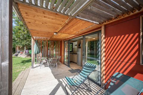 Terraza de madera con sillas y mesa en Mobile home Vancouver, Huttopia La Plage Blanche, Francia.