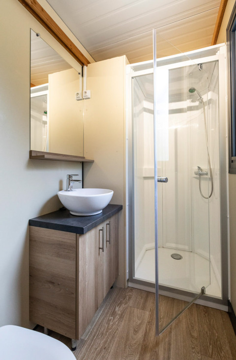 Baño en Mobile home Vancouver en Huttopia La Plage Blanche, Francia, con cabina de ducha y lavabo moderno.