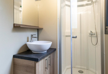 Salle de bain du Mobil-home Vancouver à Huttopia La Plage Blanche en France, avec douche et lavabo moderne.