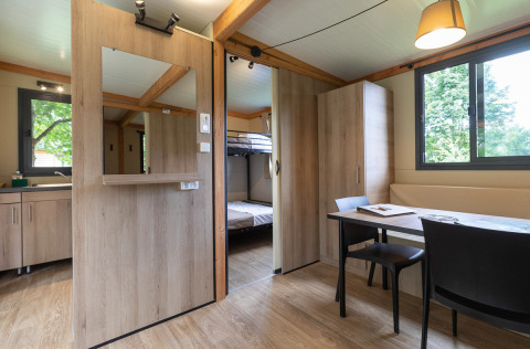 Interior de la Mobile home Vancouver en Huttopia La Plage Blanche, Francia, con mesa comedor y literas.