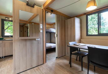 Interior de la Mobile home Vancouver en Huttopia La Plage Blanche, Francia, con mesa comedor y literas.
