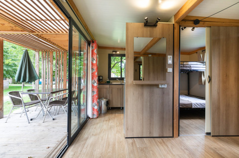Vista interior de la Mobile home Vancouver en Huttopia La Plage Blanche, con terraza, cocina y literas.