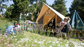 Family enjoying time outside a Canadienne safari tent in nature, surrounded by wildflowers and trees.
