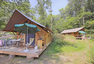 Canadienne Safari-Zelte bei Huttopia Wattwiller in Frankreich, mit Holzterrasse, Sonnenschirm und Wald.
