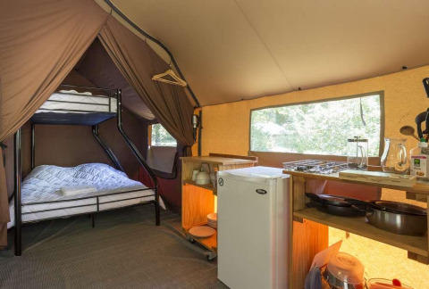 Vista interna di una tenda Canadienne a Huttopia Wattwiller, Francia, con cucina, frigo e letto a castello.