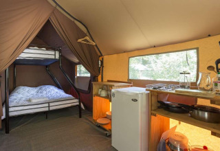 Innenansicht eines Canadienne-Zeltes im Huttopia Wattwiller mit Küche, Kühlschrank und Etagenbett.
