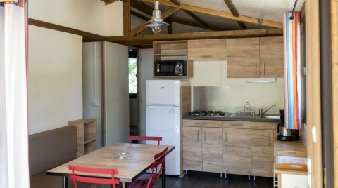 Indvendig udsigt over Chalet Evasion på Huttopia Wattwiller, Frankrig, med moderne køkken og spisebord.
