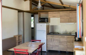 Indvendig udsigt over Chalet Evasion på Huttopia Wattwiller, Frankrig, med moderne køkken og spisebord.