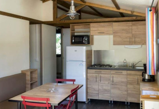 Indvendig udsigt over Chalet Evasion på Huttopia Wattwiller, Frankrig, med moderne køkken og spisebord.