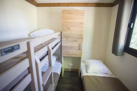 Kleine kamer in Chalet Evasion bij Huttopia Wattwiller, Frankrijk, met stapelbed en eenpersoonsbed.