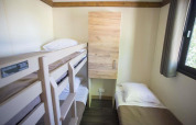 Et lille værelse i Chalet Evasion ved Huttopia Wattwiller, Frankrig, med køjeseng og enkeltseng.