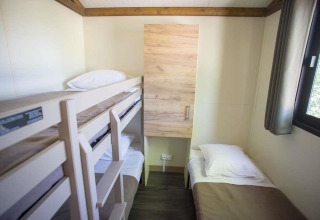 Et lille værelse i Chalet Evasion ved Huttopia Wattwiller, Frankrig, med køjeseng og enkeltseng.