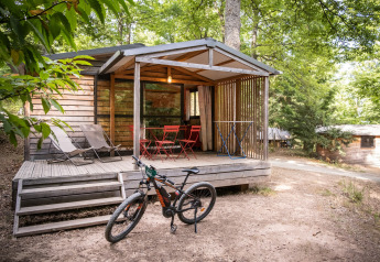 Chalet Evasion houten huisje met veranda, fiets, ligstoelen en tuinmeubilair in bosrijke omgeving.