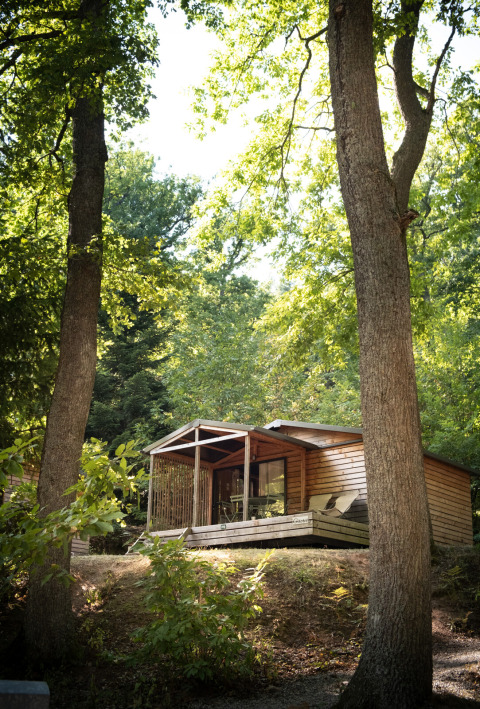 Cabaña Chalet Evasion en Huttopia Wattwiller, Francia, rodeada de árboles verdes y naturaleza.