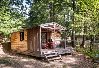 Chalet Evasion bij Huttopia Wattwiller in Frankrijk, omringd door groen bos en een houten veranda.