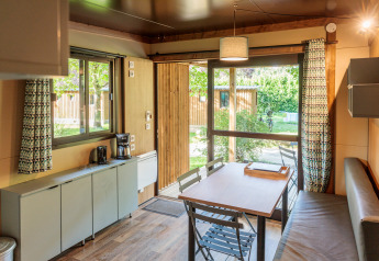 Interieur van Chalet Evasion bij Huttopia Wattwiller, Frankrijk, met eettafel en uitzicht op de tuin.