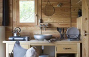 Wood-paneled kitchenette with sink, chair, and dishes inside a safari tent at Huttopia Wattwiller, France.