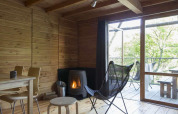 Interior acogedor de tienda safari en Huttopia Wattwiller, Francia, con estufa de leña y muebles de madera.