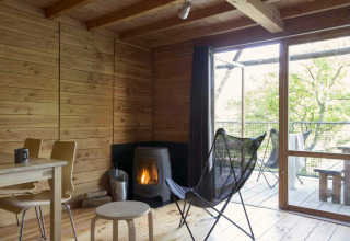 Cozy safari tent interior at Huttopia Wattwiller, France with wood stove, wooden furniture and nature view.