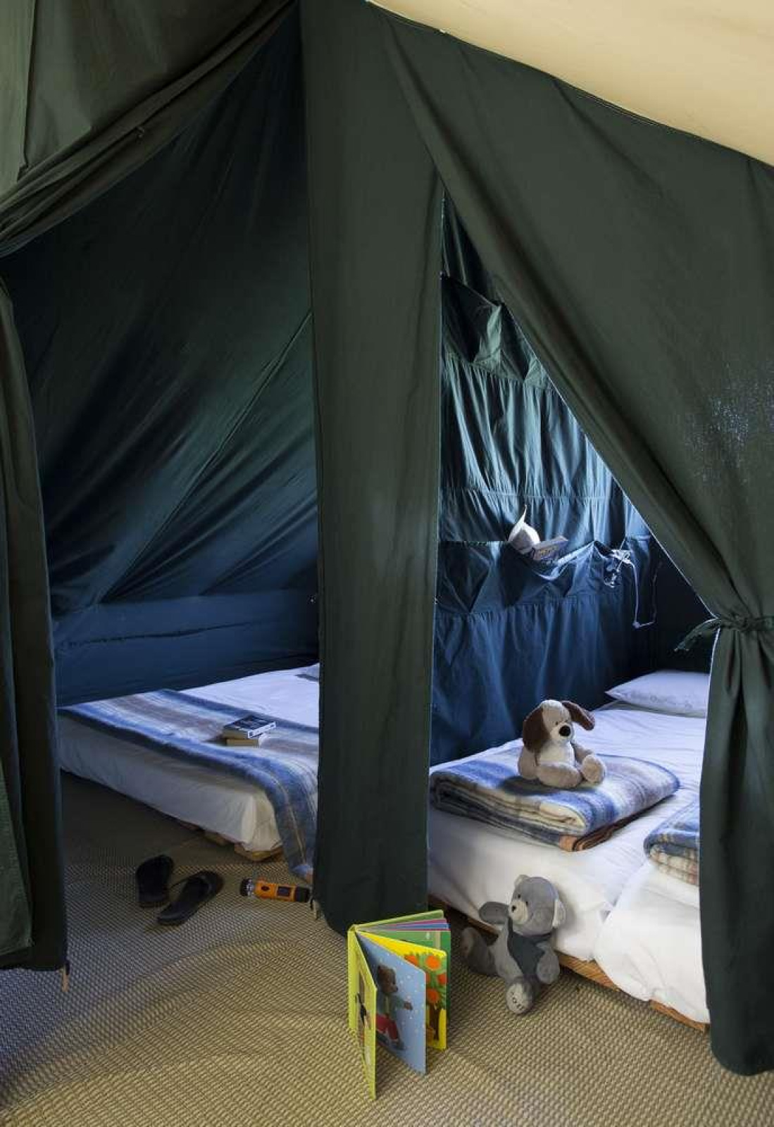 Interieur van Cahutte safaritent bij Huttopia Wattwiller met twee bedden, knuffels en een kinderboek.