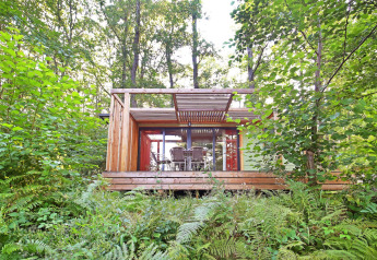 Mobile home Vancouver cabin in the forest with a spacious deck, patio furniture, and lush green surroundings.