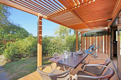 Solrig træterrasse med spisebord og stole ved Mobile home Vancouver, Huttopia Wattwiller, Frankrig.