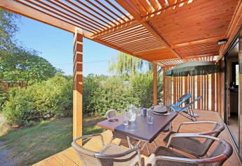 Terrasse en bois ensoleillée avec table à manger au Mobile home Vancouver, Huttopia Wattwiller, France.