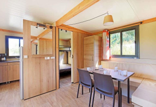 Interior luminoso y moderno de casa móvil con comedor, cocina y litera en Huttopia Wattwiller, Francia.