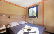 Soveværelse i Mobile home Vancouver med dobbeltseng, to puder, vindue, gardin og sollys.