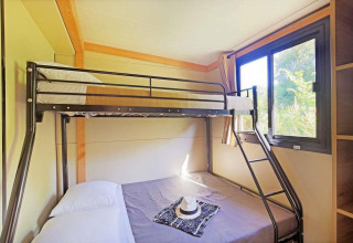 Habitación luminosa en una casa móvil con literas metálicas y ventana en Huttopia Wattwiller, Francia.