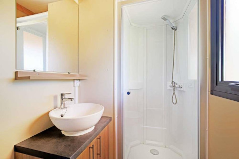 Badkamer in Mobile home Vancouver bij Huttopia Wattwiller, met douche, wastafel en groot raam.