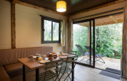 Binnenzicht van Chalet Ottawa met eettafel, stoelen en terras met uitzicht op een weelderige tuin.