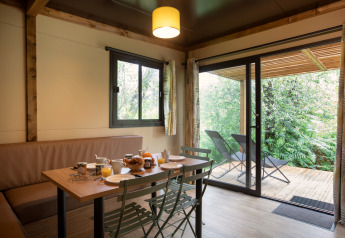 Indvendig udsigt over Chalet Ottawa med spisebord, stole og udgang til terrasse med udsigt til naturen.