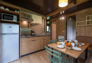 Cocina y comedor modernos en Chalet Ottawa, Huttopia Wattwiller, Francia, con desayuno preparado.